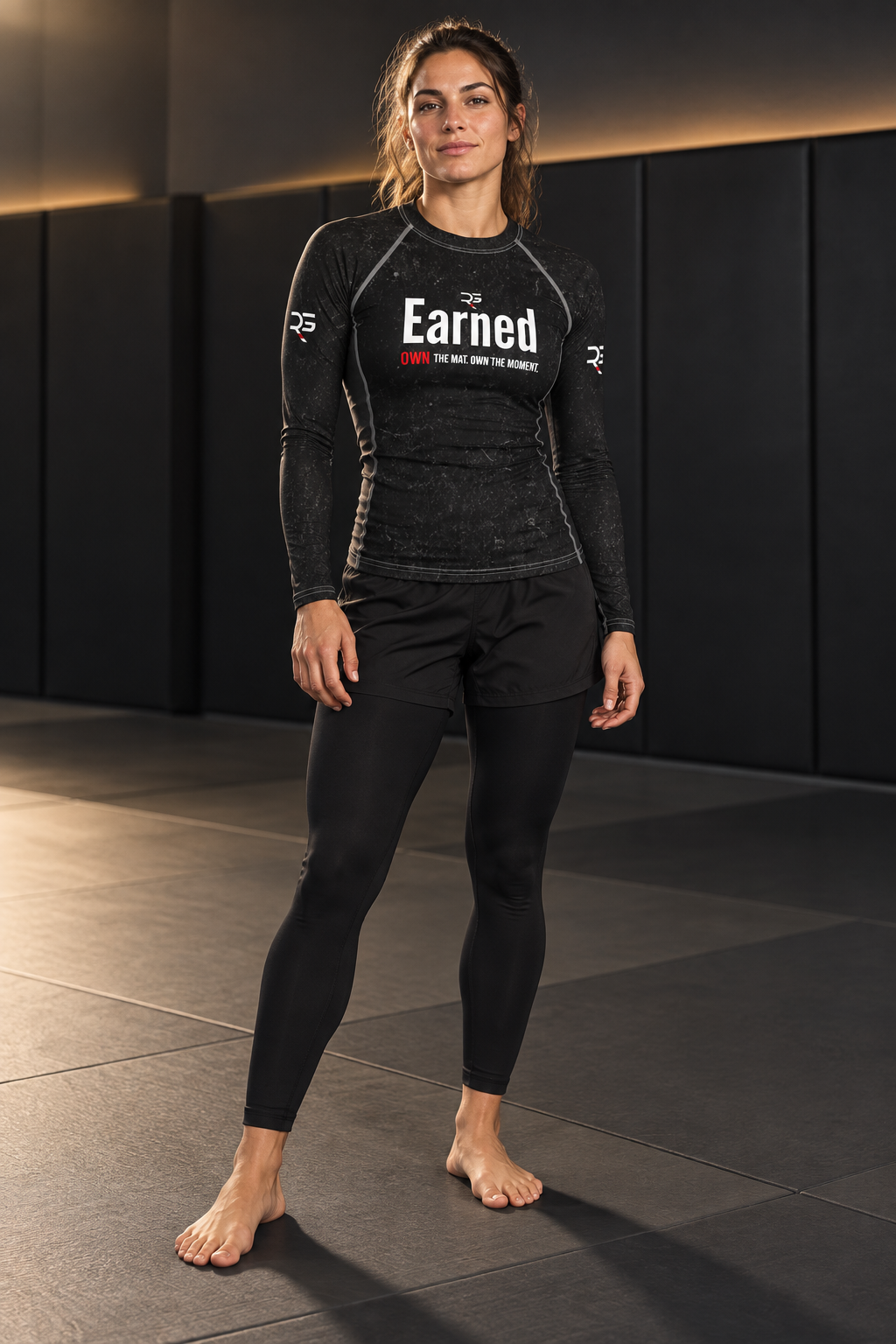 Roll Gear Earned Not Given Women’s Long Sleeve Rash Guard – Black, front view, worn in the gym.