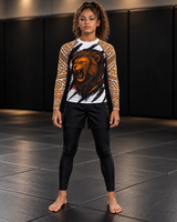 Roll Gear Lion’s Pride Long Sleeve Rash Guard – White & Gold – Youth, front view on a teen girl, lion chest graphic.