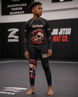 Child wearing a black and red 'Cold Blooded' jiu-jitsu outfit in a gym setting.