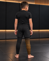 Roll Gear Lion's Pride Kids BJJ Spats – Black & Gold, back view on a boy.