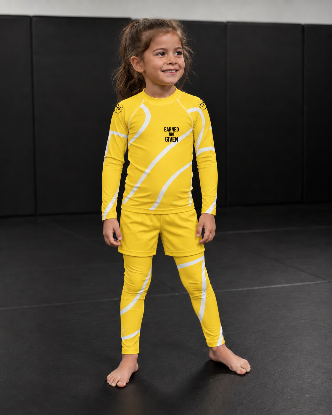Roll Gear Yellow Swirl Spats – Yellow/White – Kids, front view on a young girl in the matching rash guard.