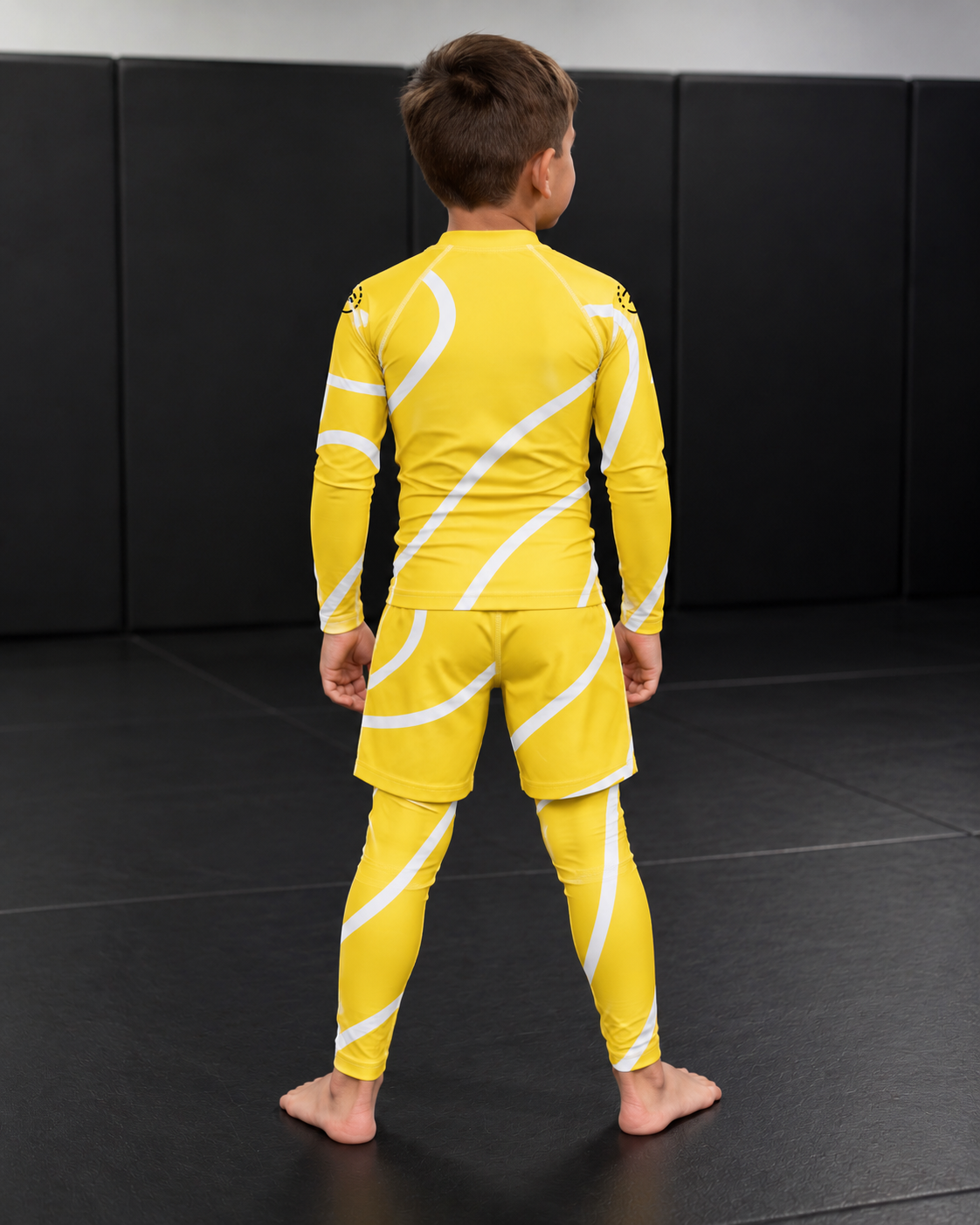 Roll Gear Yellow Swirl Spats – Yellow/White – Kids, back view on a child in the matching rash guard.