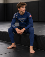 Roll Gear Youth Air Force Compression Spats – Navy, boy sitting on the mat in the matching rash guard.
