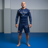Man wearing Air Force-themed athletic wear standing on a blue mat against a gray wall.