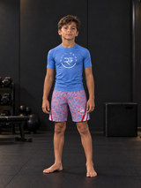 Roll Gear Stars & Scribbles Grappling Shorts – Boys', boy standing in a gym, front view.