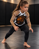 Roll Gear Lion’s Pride Long Sleeve Rash Guard – White & Gold – Kids, girl in a fighting stance on the mat.