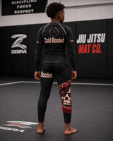 Person wearing a black and red jiu jitsu uniform with visible branding in a gym setting.