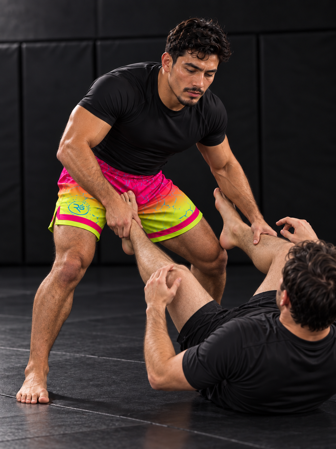 Roll Gear Neon Lava Grappling Shorts – Men's, pink-to-yellow fade, worn passing guard in a drill.