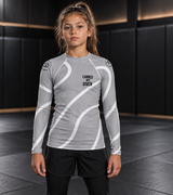Roll Gear Grey Swirl Rash Guard – Grey/White – Youth, front view on a girl standing on the mat.