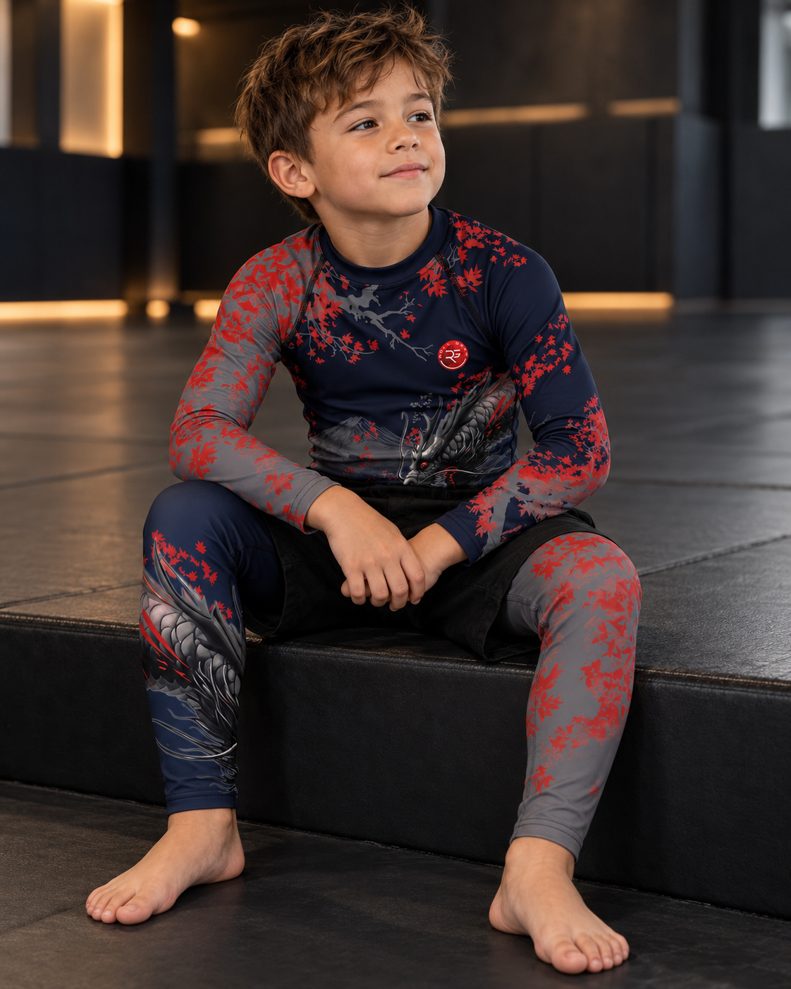 Roll Gear Shadow Dragon Warrior Kids Rash Guard and Spats – Dark Navy & Crimson, boy seated on a gym bench.