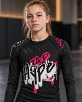 Roll Gear Tap Hype – Pink Edition Kids Long-Sleeve BJJ Rash Guard, close-up of the Tap Hype chest graphic.