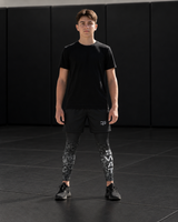 Roll Gear Youth SWAT Compression Spats, SWAT lettering down the leg, worn by a youth athlete on the mat.