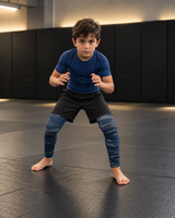 Roll Gear Kids Navy Compression Spats, boy in a fighting stance on the mat.