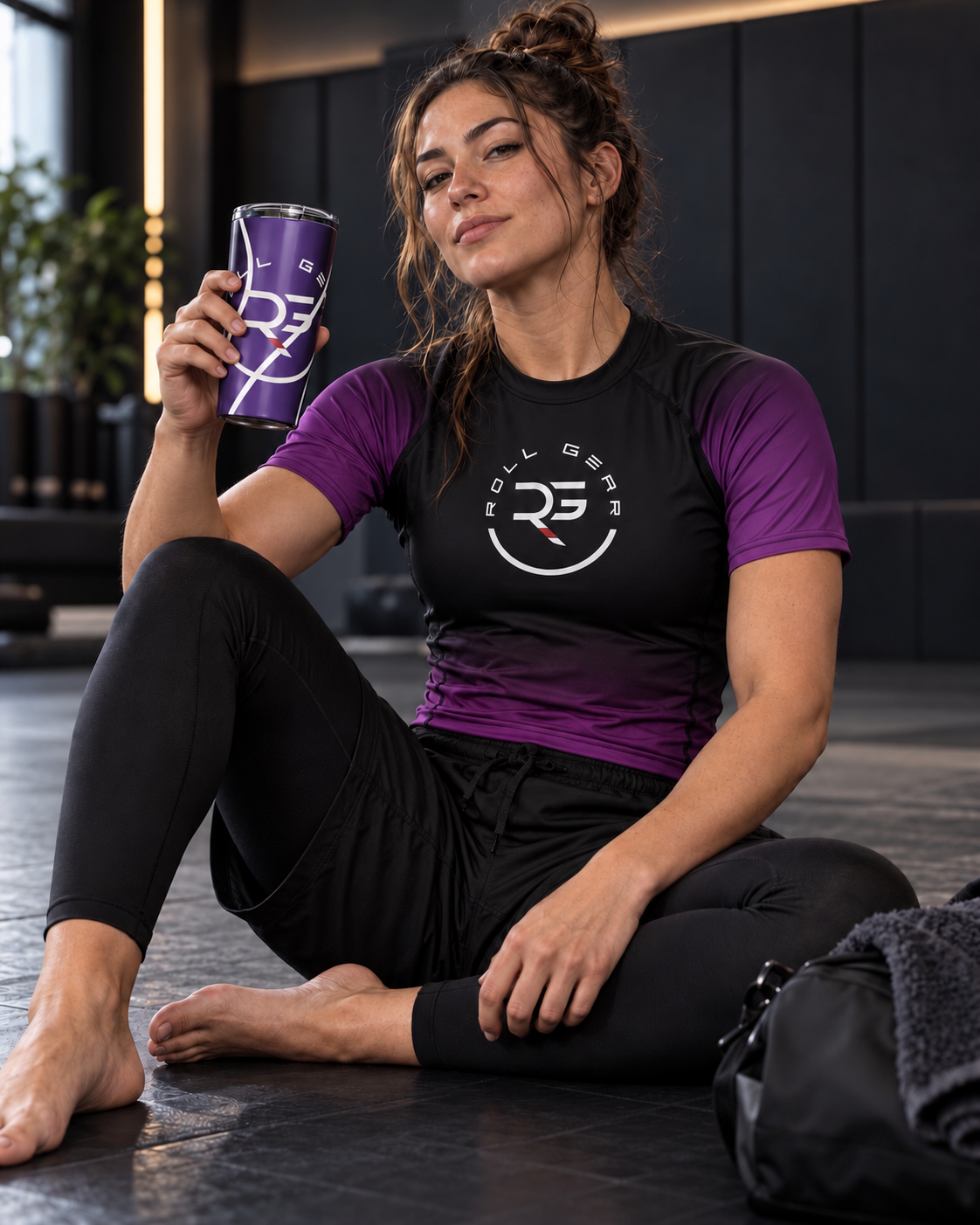 Roll Gear Ranked Series Tumbler – 20oz Stainless Steel – Glossy Purple Finish, held by a woman sitting on the mat.