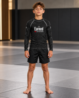 Roll Gear Earned Not Given Long Sleeve Rash Guard – Black – Youth, front view on a boy, Earned chest print.
