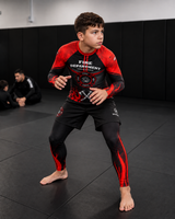 Roll Gear Kids Fire Department Compression Spats – Black with Red Flames, boy in a grappling stance.