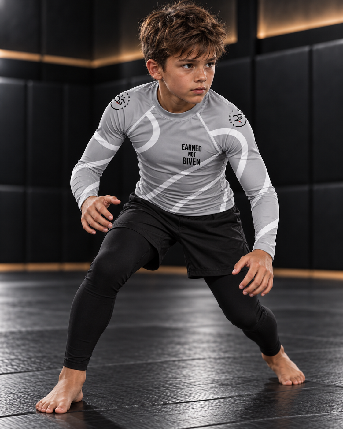 Roll Gear Grey Swirl Rash Guard – Grey/White – Youth, worn by a boy in a grappling stance on the mat.