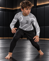 Roll Gear Grey Swirl Rash Guard – Grey/White – Youth, worn by a boy in a grappling stance on the mat.