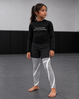 Roll Gear Grey Swirl Spats – Grey/White – Kids, worn by a girl with a black rash guard on the mat.