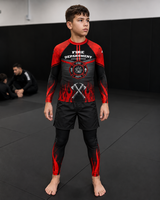 Roll Gear Kids Fire Department Compression Spats – Black with Red Flames, front view on a boy in the matching rash guard.
