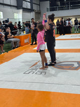 Woman and child on a wrestling mat with spectators in the background