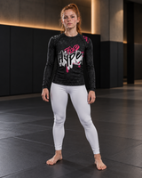 Roll Gear Tap Hype – Pink Edition Long-Sleeve BJJ Rash Guard, front view, worn with white leggings on the mat.