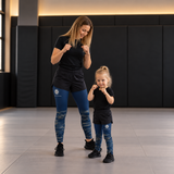 Roll Gear Kids Navy Compression Spats, young girl standing with an adult on the mat.