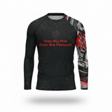 Roll Gear Evolve or Repeat Men’s Long Sleeve Rash Guard, angled flat front view, Own the Mat chest text.