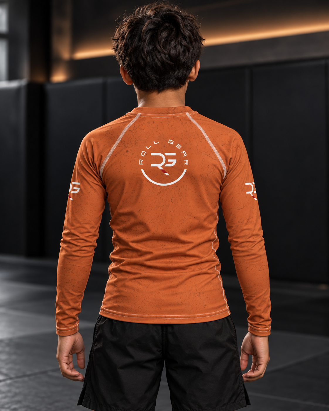 Roll Gear Earned Not Given Long Sleeve Rash Guard – Burnt Orange – Youth, back view on a boy, Roll Gear emblem.