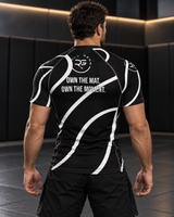 Roll Gear Black Swirl Short Sleeve Rash Guard – Black/White – Adult Unisex, back view on a man, Own the Mat text.