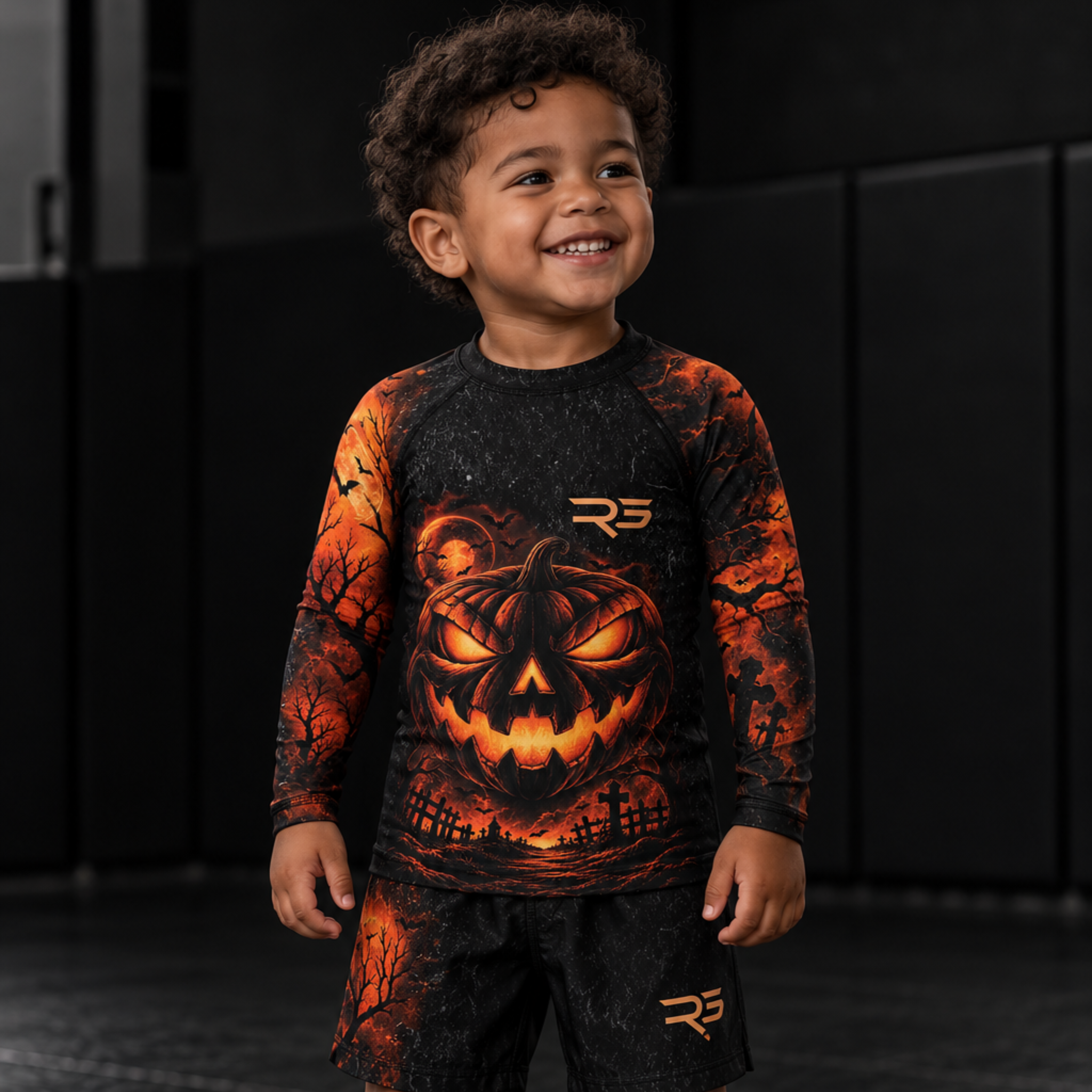 Roll Gear Kids Tap or Treat Long Sleeve Rash Guard, smiling boy standing on the mat, front view.