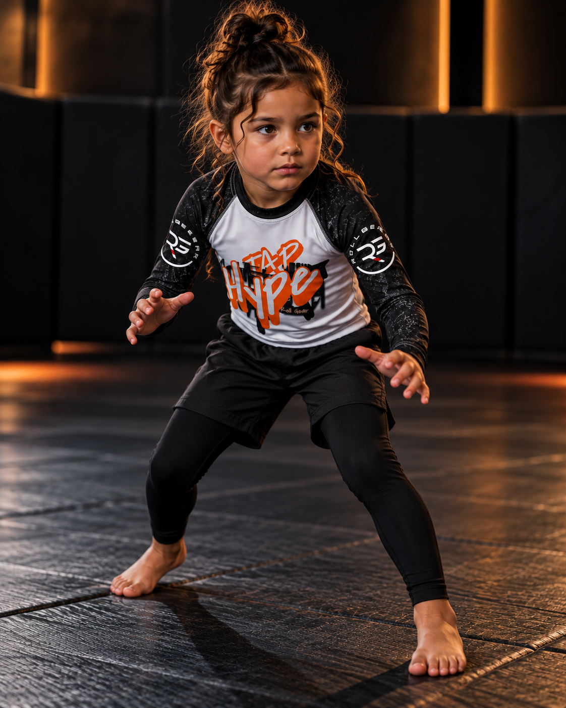 Roll Gear Tap Hype Long Sleeve Rash Guard – Orange & White – Kids, worn by a girl stepping into a stance on the mat.