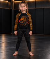 Roll Gear Lion’s Pride Long Sleeve Rash Guard – Black & Gold – Kids, front view on a girl, lion graphic.