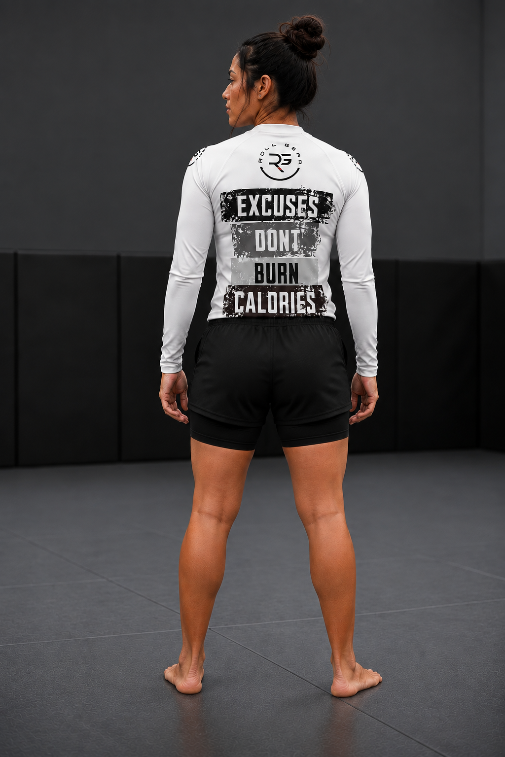Roll Gear Excuses Don’t Burn Calories rash guard and women's 2-in-1 grappling shorts, back view on the mat.