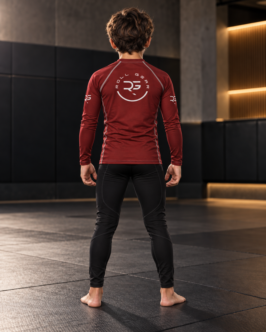 Roll Gear Earned Not Given Long Sleeve Rash Guard – Deep Red – Youth, boy standing on the mat, back view.