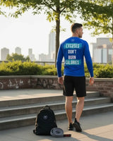 Man in a blue long-sleeve Roll Gear rash guard reading Excuses Don't Burn Calories, standing on a city sidewalk near a brick wall