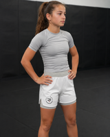 Person wearing a gray athletic shirt and white shorts with a logo on a black background