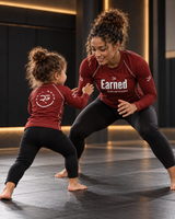 Roll Gear Earned Not Given Long Sleeve Rash Guard – Deep Red, woman and girl drilling together on the mat.