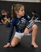 Child in a navy-themed athletic outfit on a black mat