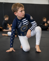 Child in a navy and white athletic outfit on a black mat