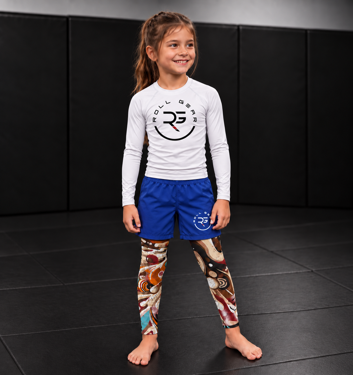 Roll Gear Never Accept Training Spats – Black/Multicolor – Kids, worn with shorts and a Roll Gear rash guard.