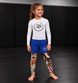 Roll Gear Never Accept Training Spats – Black/Multicolor – Kids, worn with shorts and a Roll Gear rash guard.