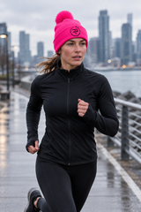 Roll Gear Beanie, neon pink pom-pom beanie on a woman jogging by the water.