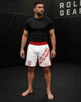 Roll Gear Own the Mat BJJ Fight Shorts – Red & White, worn by a man standing in an academy.