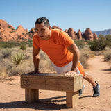 Roll Gear white athletic performance shorts with orange side panels and waistband. Features text "OWN THE MAT. OWN THE MOMENT."