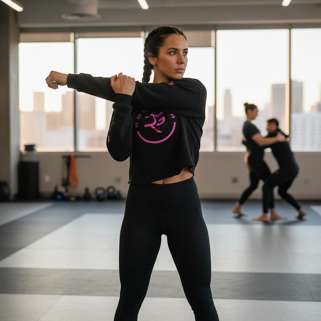 Roll Gear Women’s Crop Hoodie – Pink Edition, woman stretching in a gym.