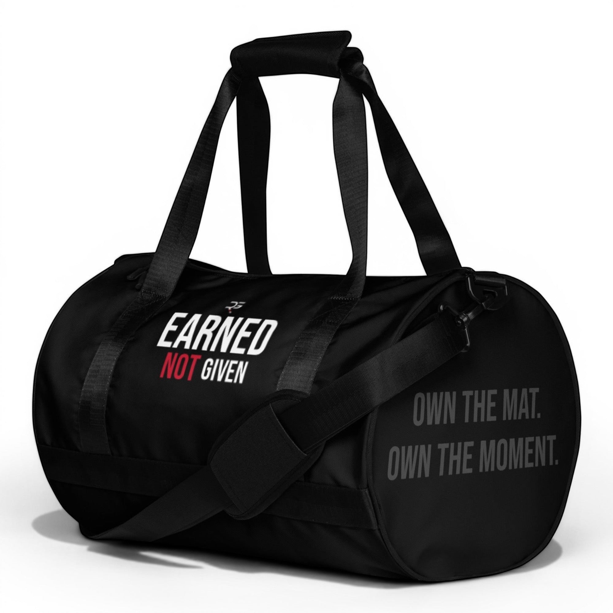 Black polyester duffel bag by Roll Gear with "EARNED NOT GIVEN" graphic and "OWN THE MAT. OWN THE MOMENT." text.