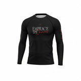 Roll Gear black long sleeve youth performance rash guard with "Embrace the Chaos" graphic and red accents on sleeve.