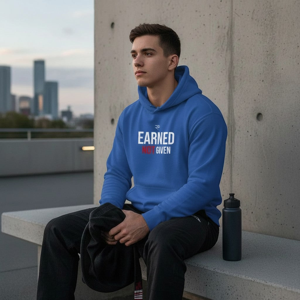 Roll Gear blue heavyweight cotton-blend hoodie with "Earned Not Given" graphic print on chest. Model sitting outdoors.