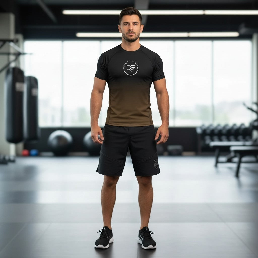 Roll Gear Brown Fade Rash Guard – Brown/Black – Adult Short Sleeve, worn by a man standing in a gym.